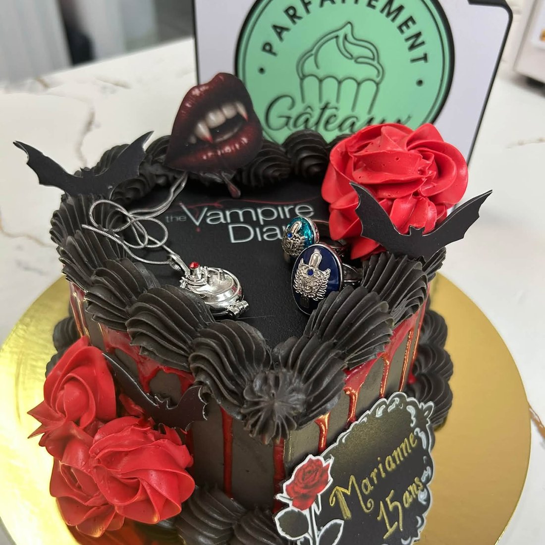 Un gâteau noir à thème, décoré de roses rouges et de chauves-souris